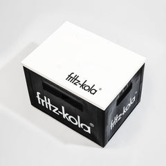 Schwarze fritz-kola Getränkekiste mit weißem Schriftzug an den Seiten, darauf liegt weißer Holz-Deckel mit "fritz-kola" Logo